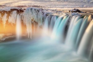 Cascada imponente al atardecer con niebla y reflejos dorados