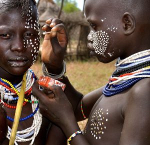 Retrato de dos personas con pintura facial tribal y collares coloridos en África