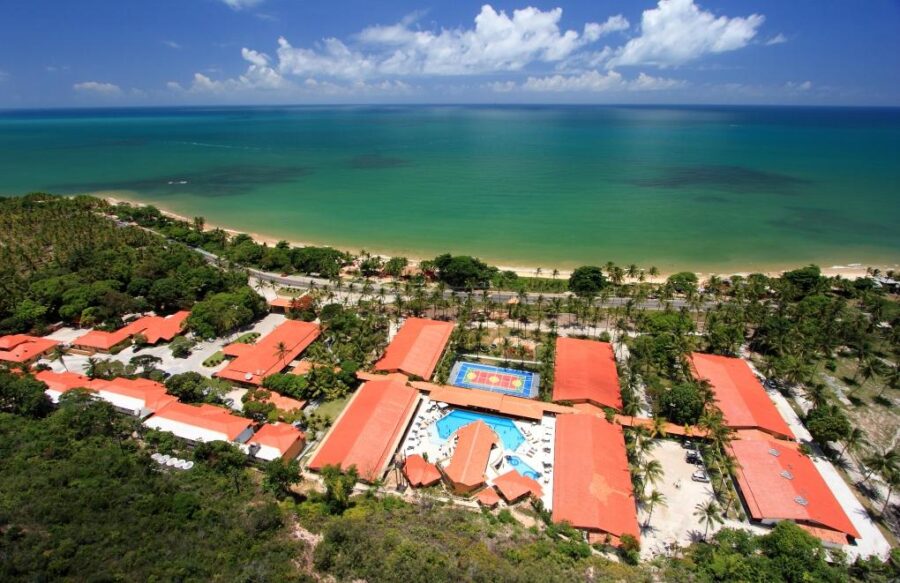Resort all inclusive en Porto Seguro frente al mar Vista aérea de resort all inclusive en Porto Seguro, Brasil, con piscina y acceso directo a la playa.