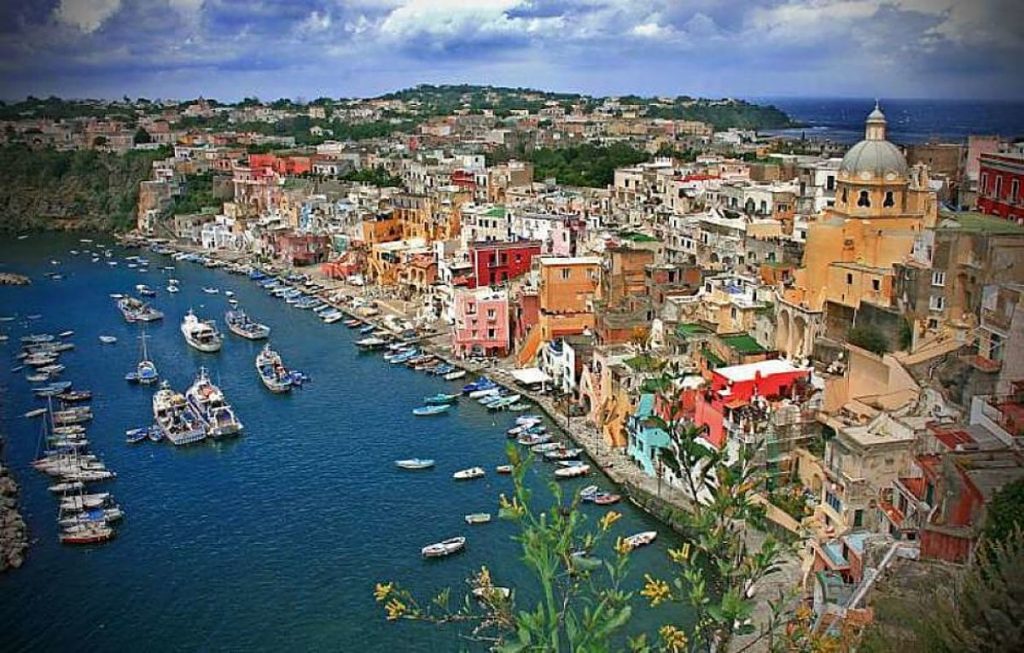 Vista aérea de la costa de Napoles, con sus coloridas fachadas y barcos y veleros.