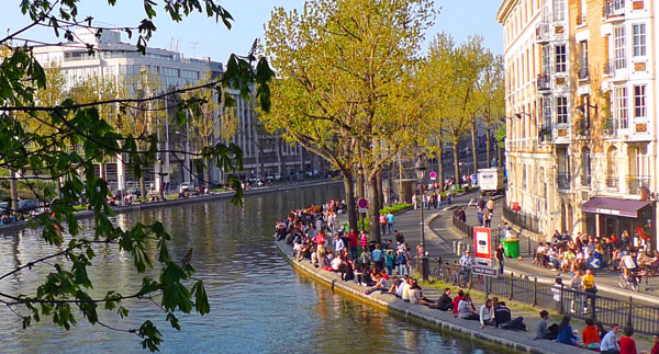 Canal Saint-Martin en París, con puentes metálicos y reflejos sobre el agua al atardecer.