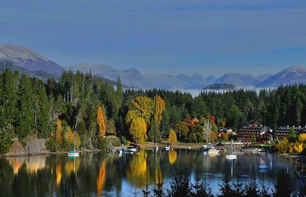 Bahía Manzano en Villa La Angostura, Patagonia argentina Vista panorámica de Bahía Manzano en Villa La Angostura con bosques, montañas y barcos reflejados en las aguas del Lago Nahuel Huapi