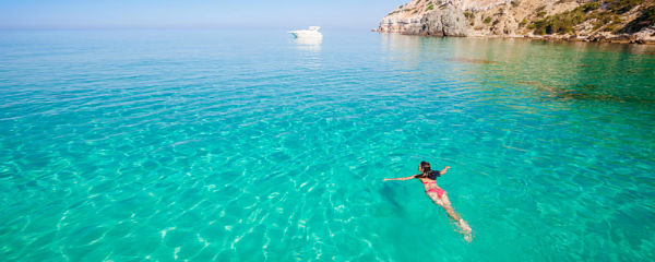 Playa de aguas cristalinas con mar turquesa y persona nadando en un destino paradisíaco ideal para viajar
