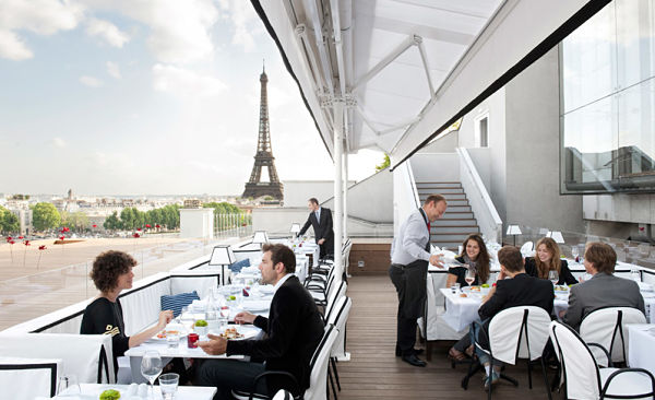torre eiffel al fondo y mesas con personas comiendo 
