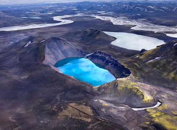 Cráter volcánico con lago azul en Islandia Lago azul dentro de un cráter volcánico en Islandia, rodeado de montañas y paisajes áridos.