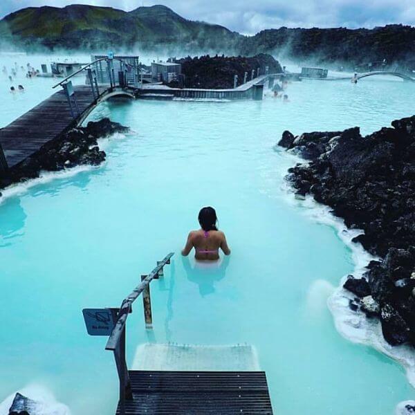Blue Lagoon, aguas termales de Islandia Persona disfrutando de las aguas termales en la Laguna Azul de Islandia, rodeada de rocas volcánicas.