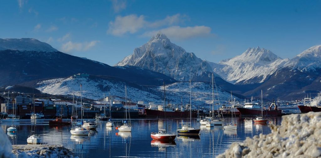 Puerto de Ushuaia con veleros y montañas nevadas al fondo