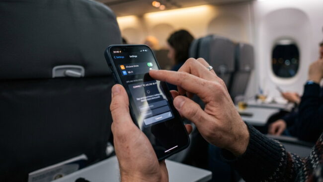 Pasajero conectando su teléfono al WiFi de un avión durante el vuelo
